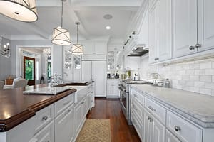 Beautiful elongated Robbinsville kitchen island with center sink and 3 main lights over the cherry wood counters.