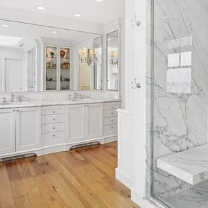 Beautiful luxury bath with natural wood floors and white Carrara marble shower and matching vanity.