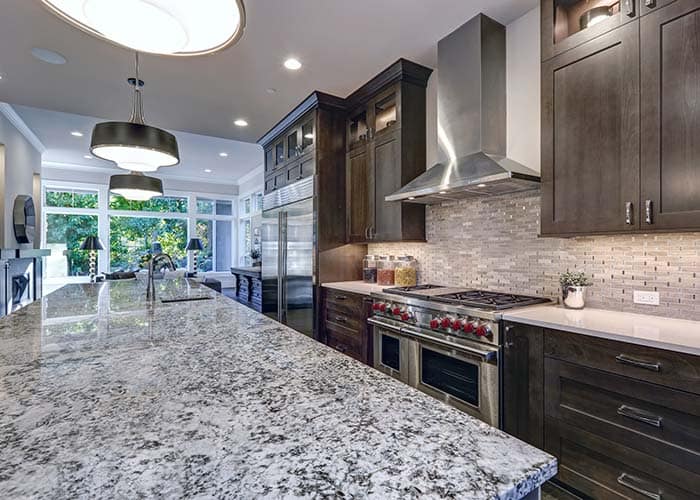 Stunning renovated kitchen in Bay Head with premium granite island countertop and island sink, paired with darker custom cabinets and high-end appliances.